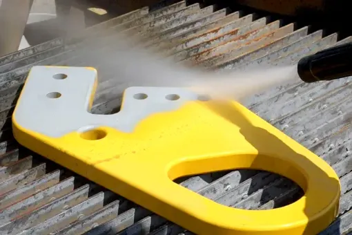 A yellow and white object is being sprayed with a high pressure washer.