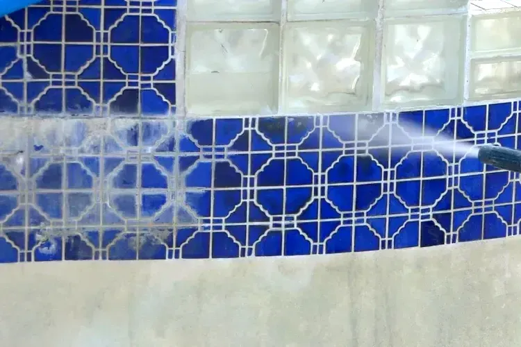 A person is cleaning a blue tile wall with a high pressure dustless blasting system