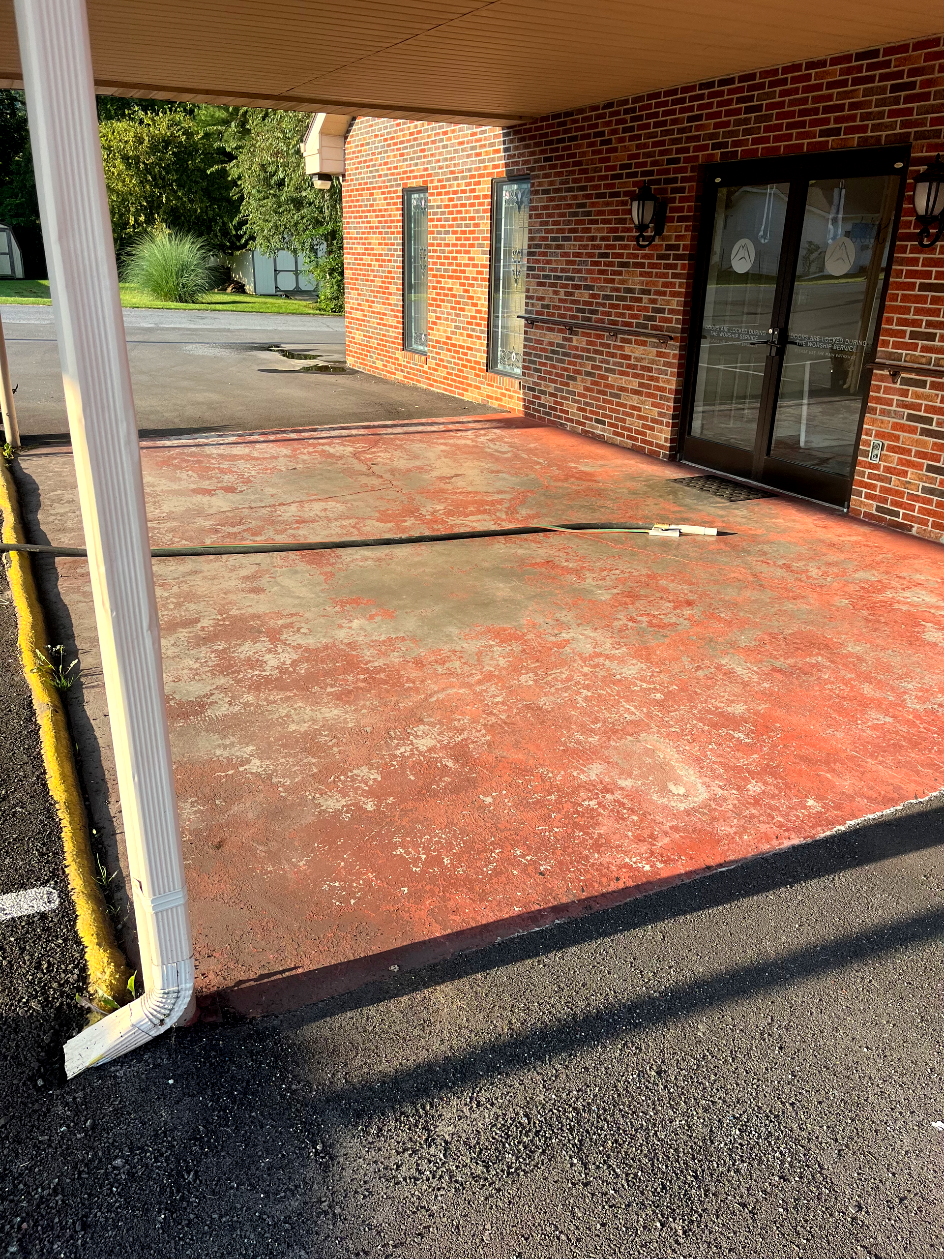 A brick building with a red concrete driveway in front of it.