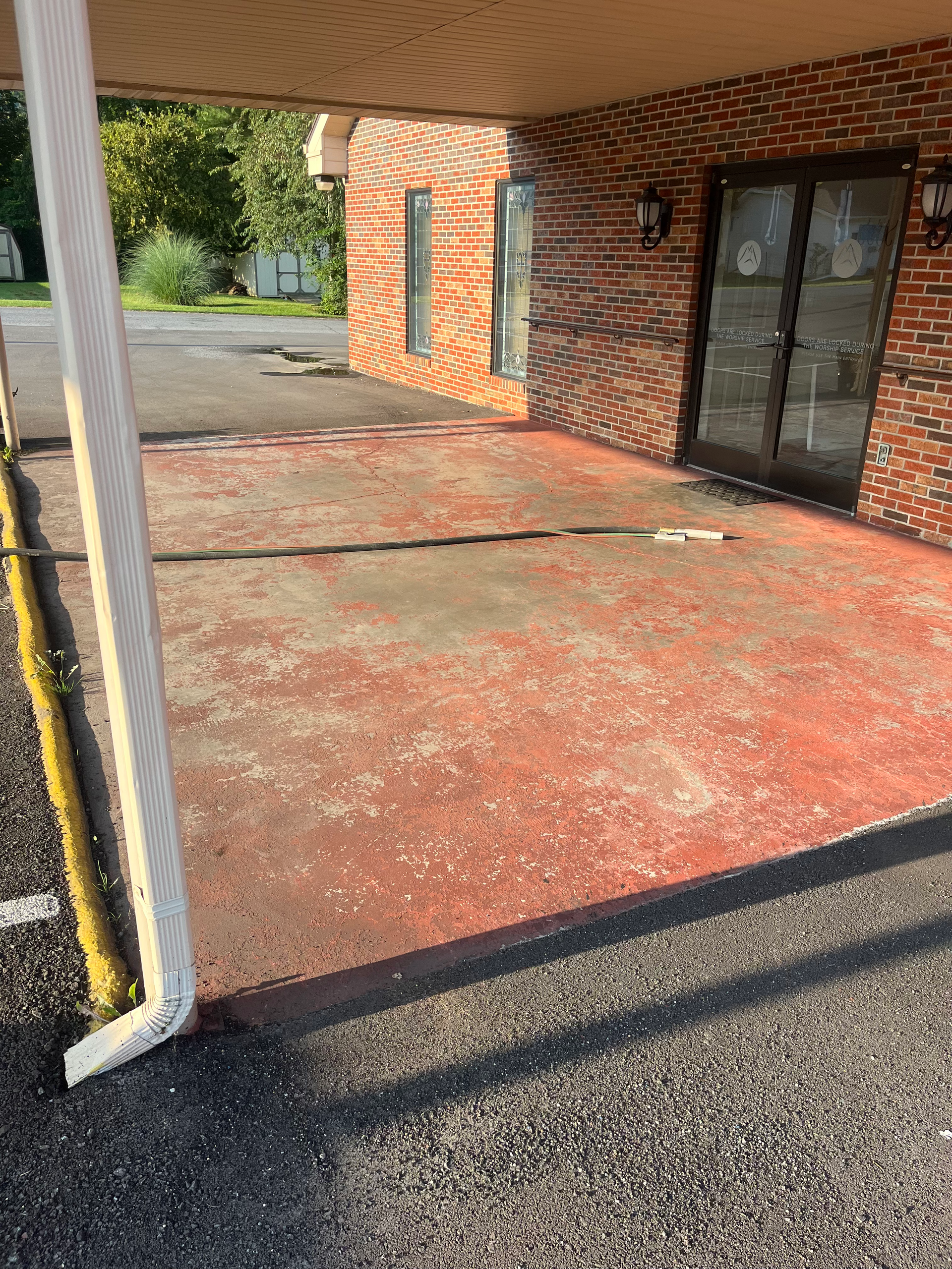 A brick building with a red concrete driveway in front of it.