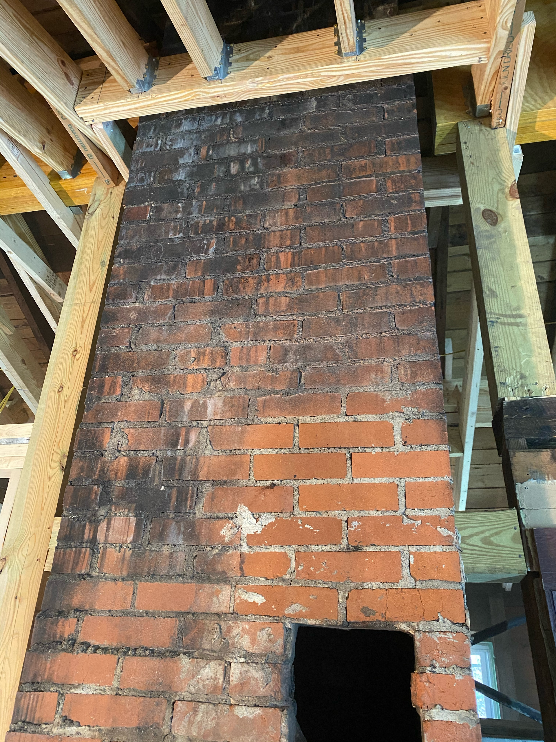 A brick chimney is being built in a building under construction.