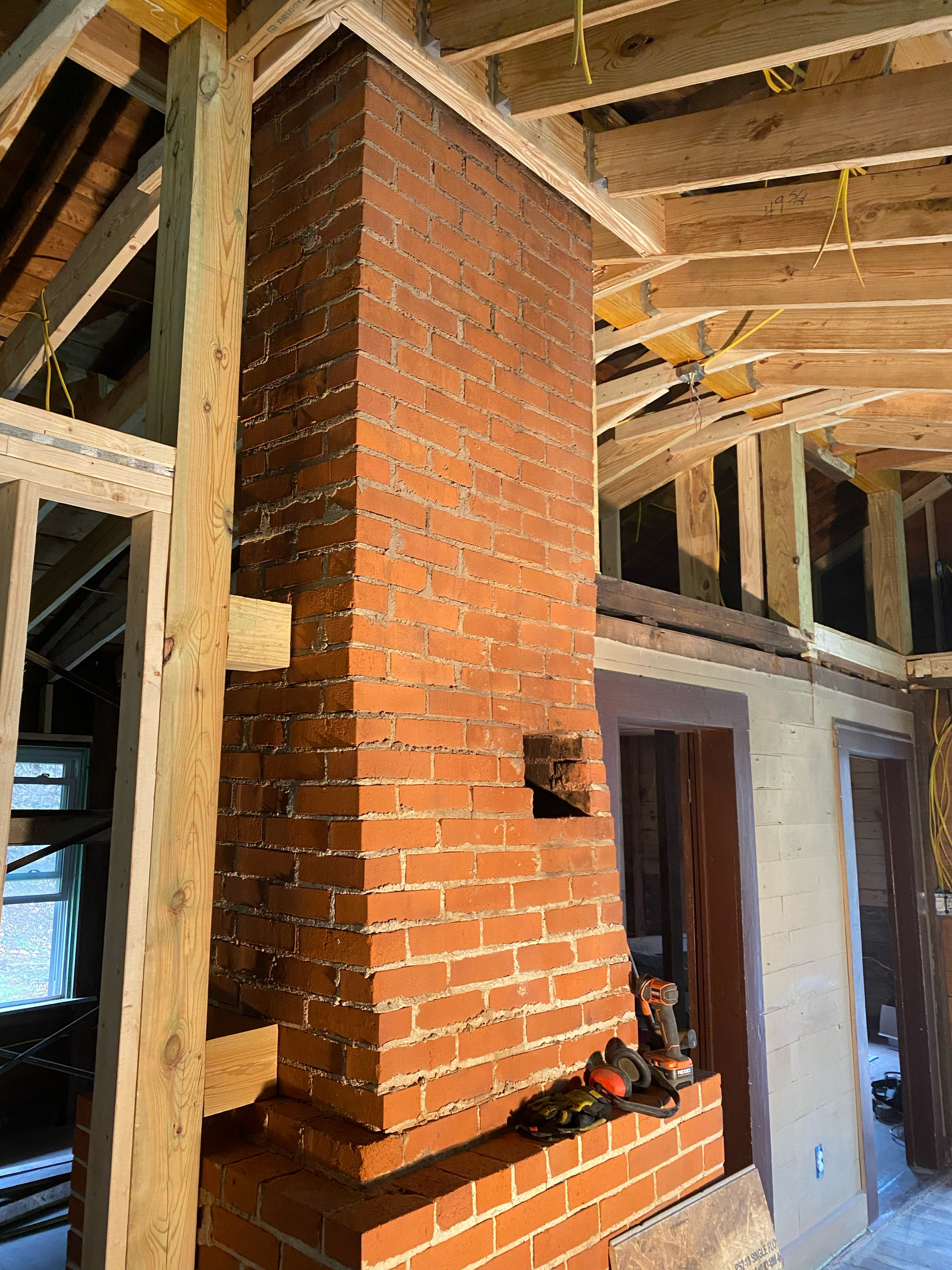 A brick chimney is being built in a house under construction.