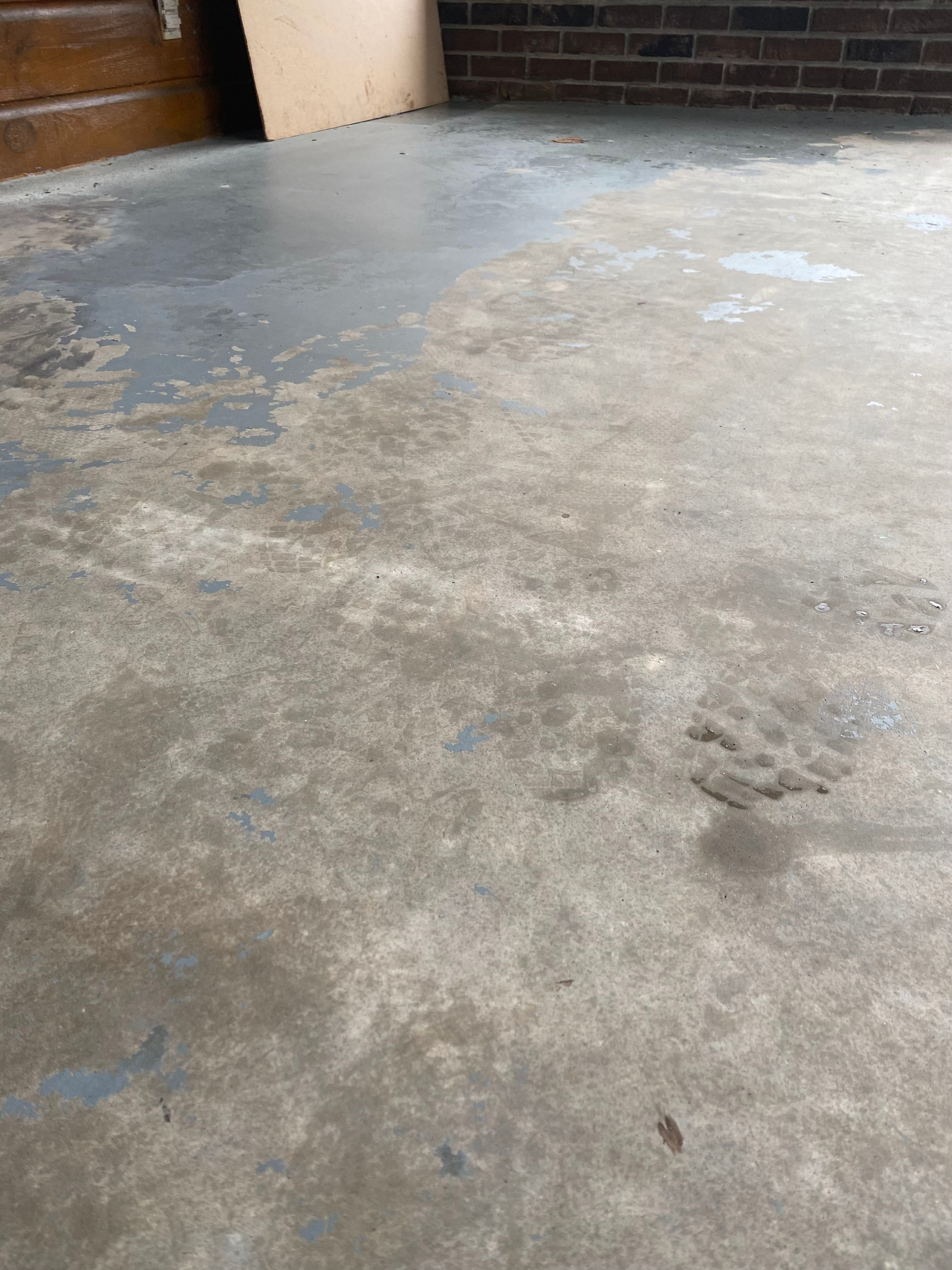 A close up of a concrete floor in a garage with a brick wall in the background.