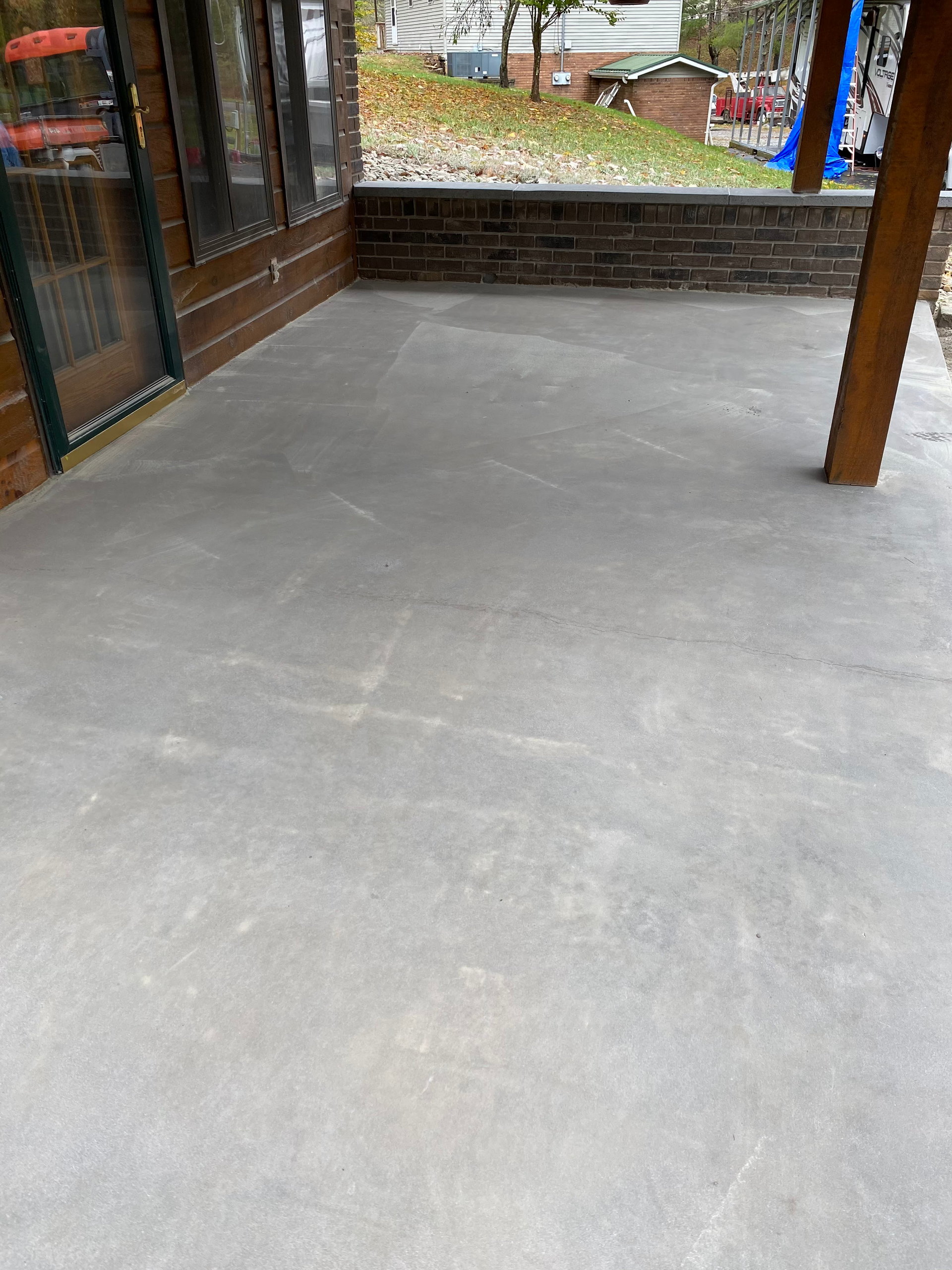 A patio with a concrete floor and a brick wall.