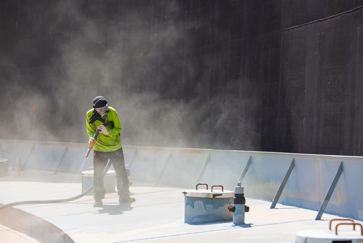 A man is spraying powder on a concrete surface.