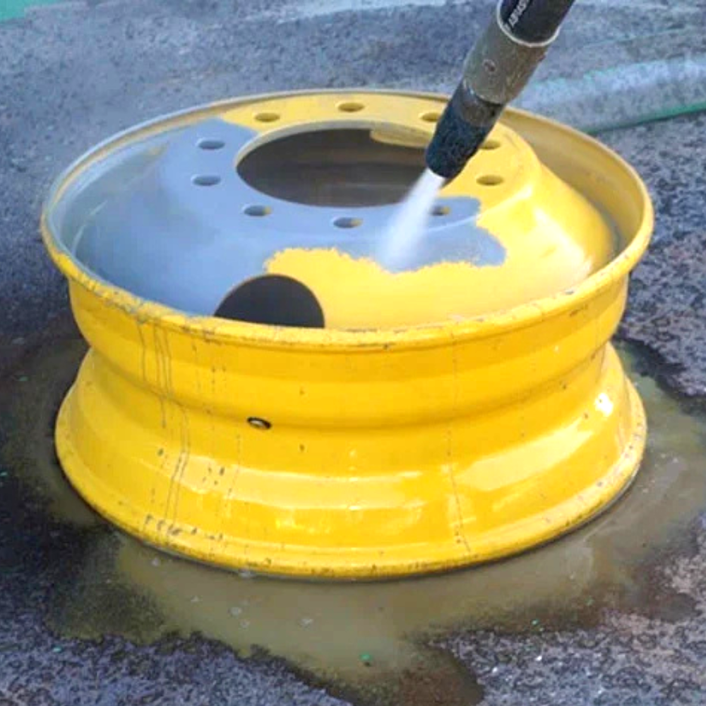 A yellow wheel is being cleaned with a high pressure dustless sandblasting system by Lyons Blasting & Restoration