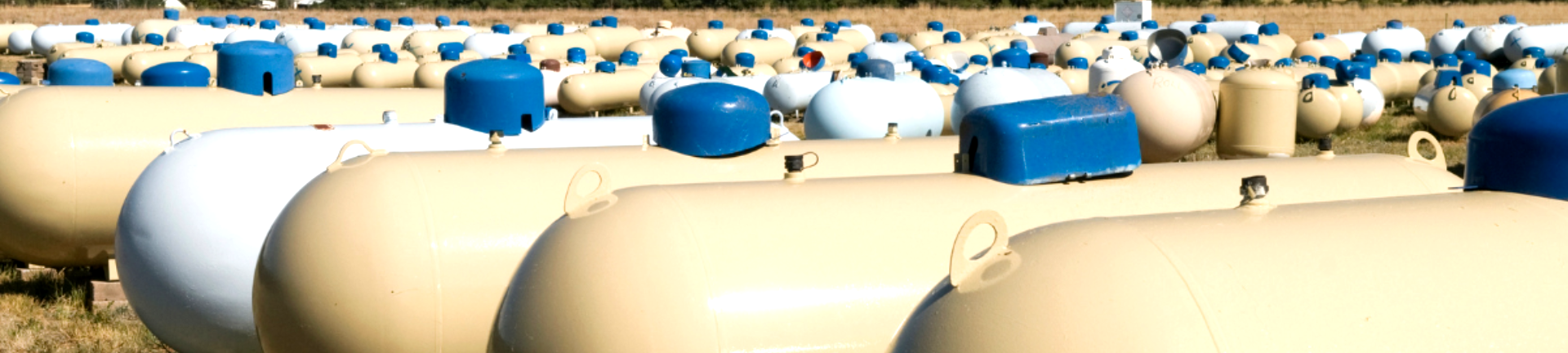 A row of propane tanks sitting next to each other in a field.