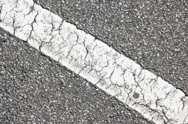 A close up of a cracked white line on a road.