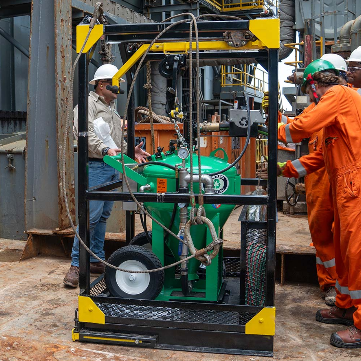 Two men in orange jumpsuits are working on a green machine