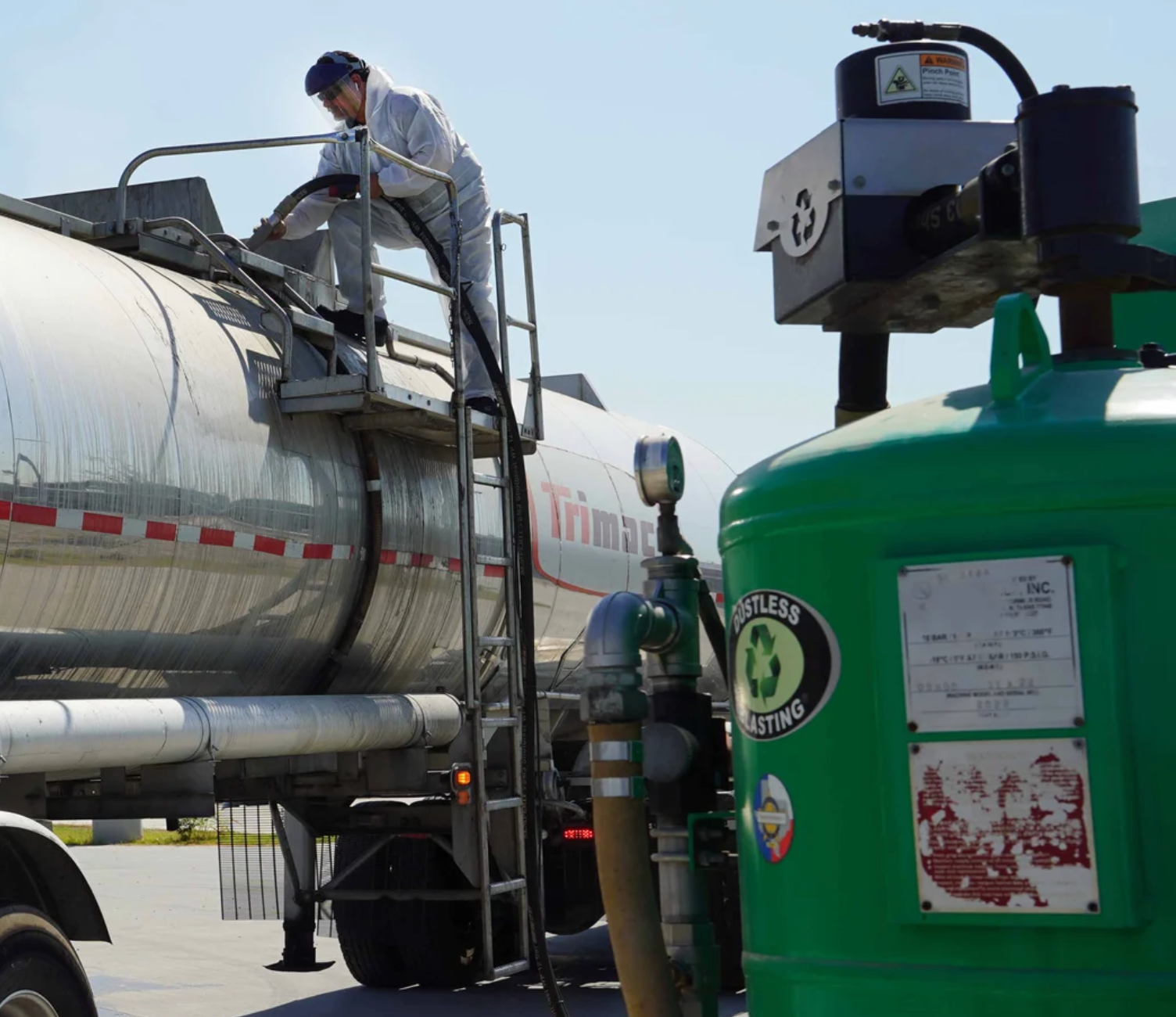 A man is standing on top of a tanker truck