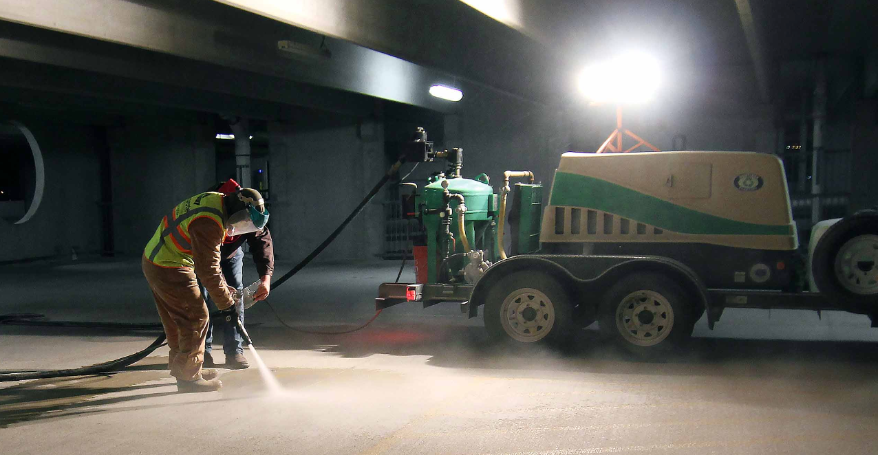 A man is standing next to a machine in a parking garage.