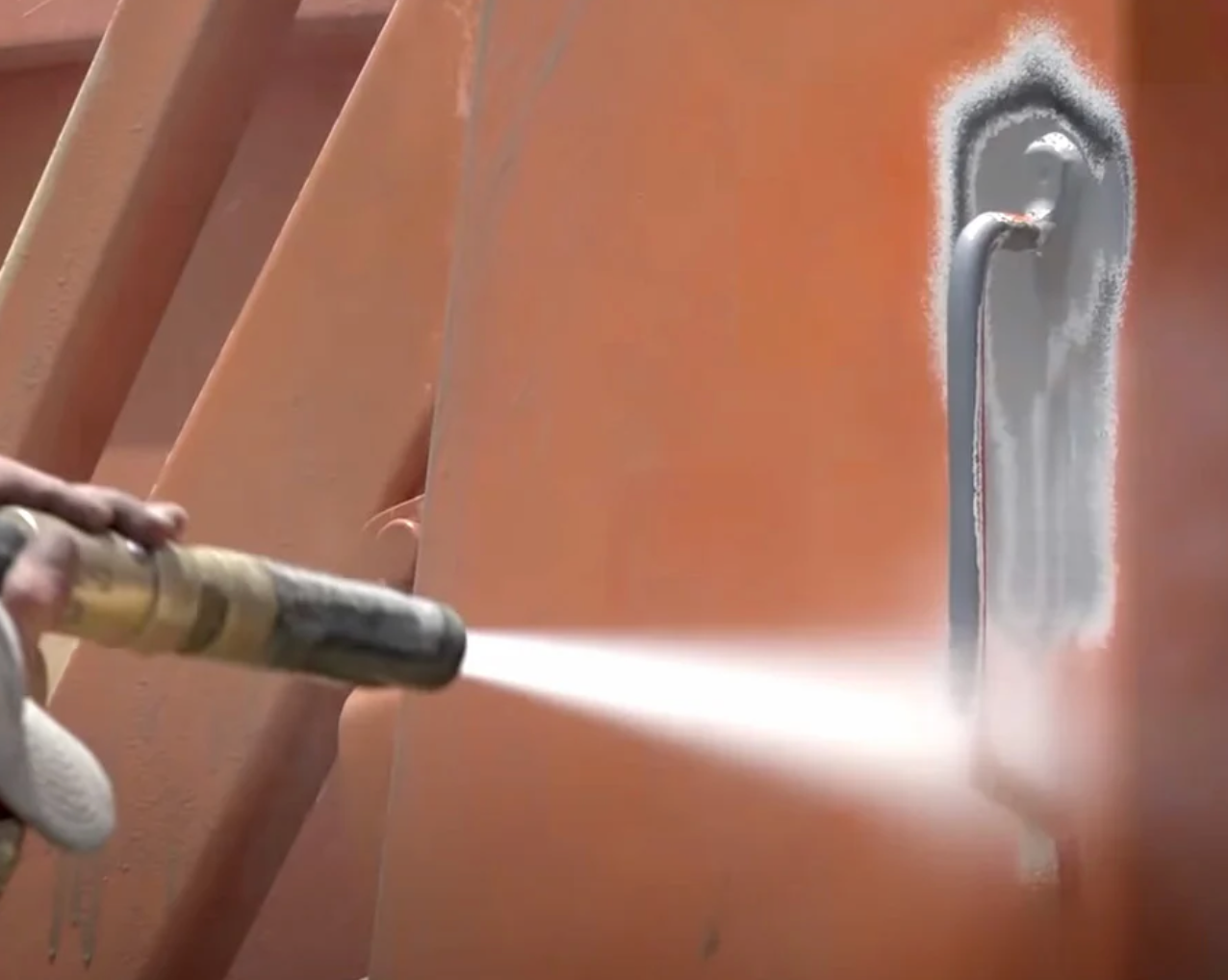 Sandblasting a powder coating and primer off of metal.