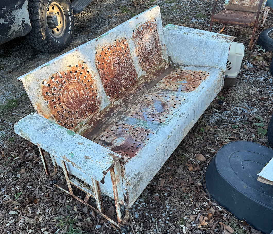 An old rusty couch is sitting on the ground.