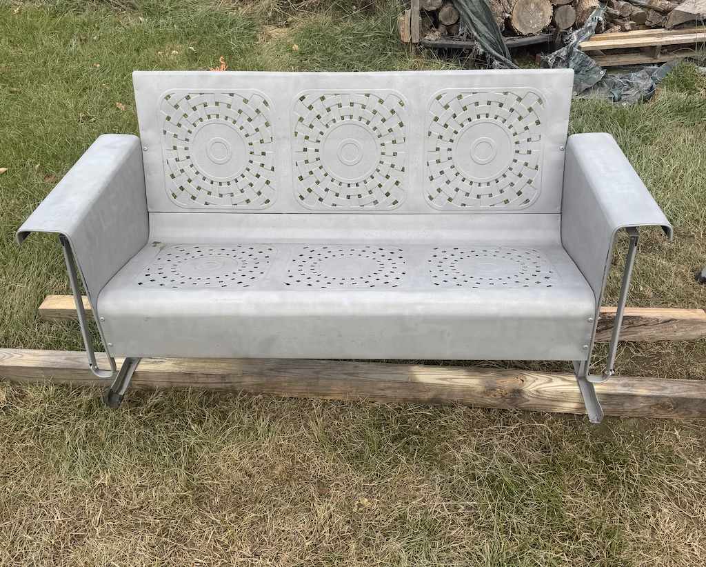 A gray couch is sitting on top of a lush green field.