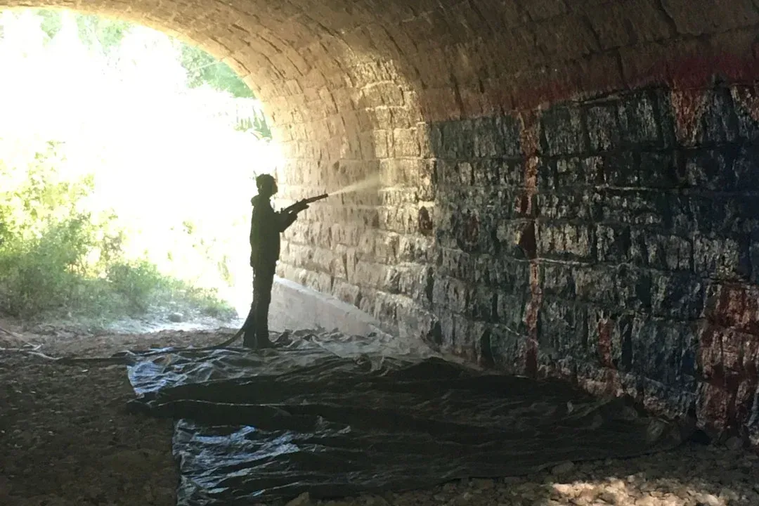 A man is standing in front of a wall with graffiti on it.