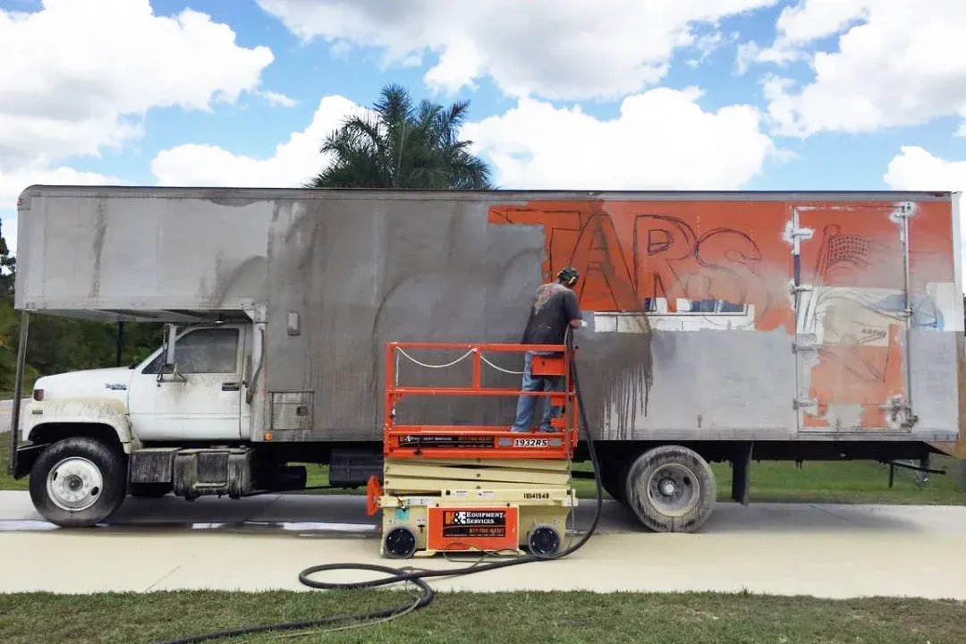 A man is cleaning a truck with a scissor lift.