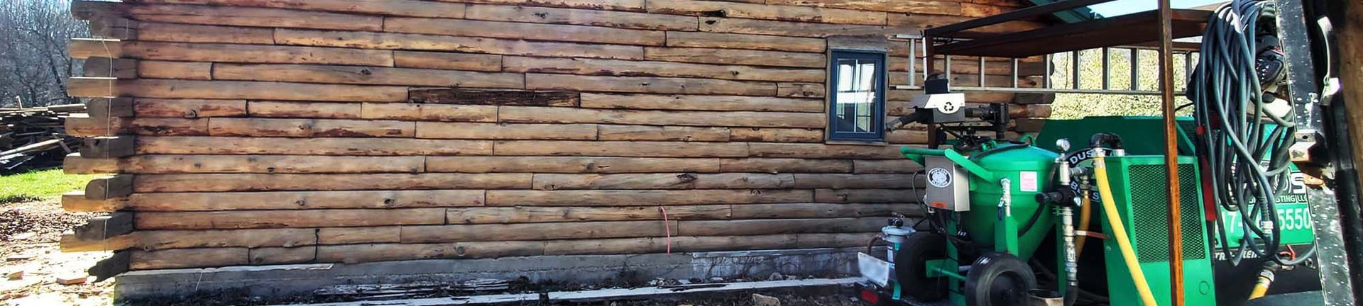 A green tractor is parked in front of a brick building.