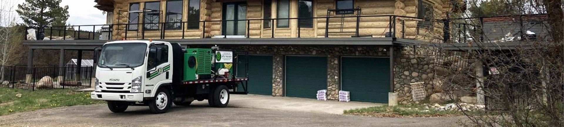 A white truck is parked in front of a log cabin
