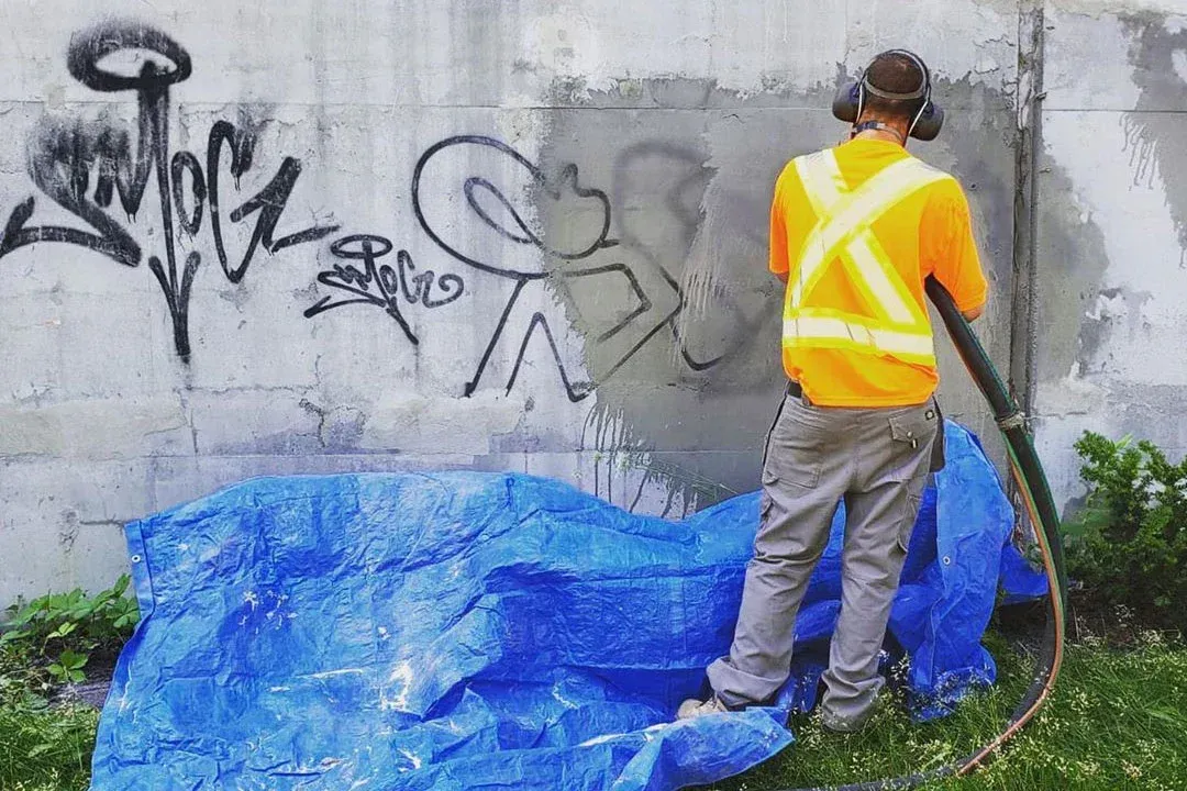 A man is standing in front of a wall with graffiti on it.