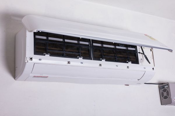 A white air conditioner is hanging on a white wall.