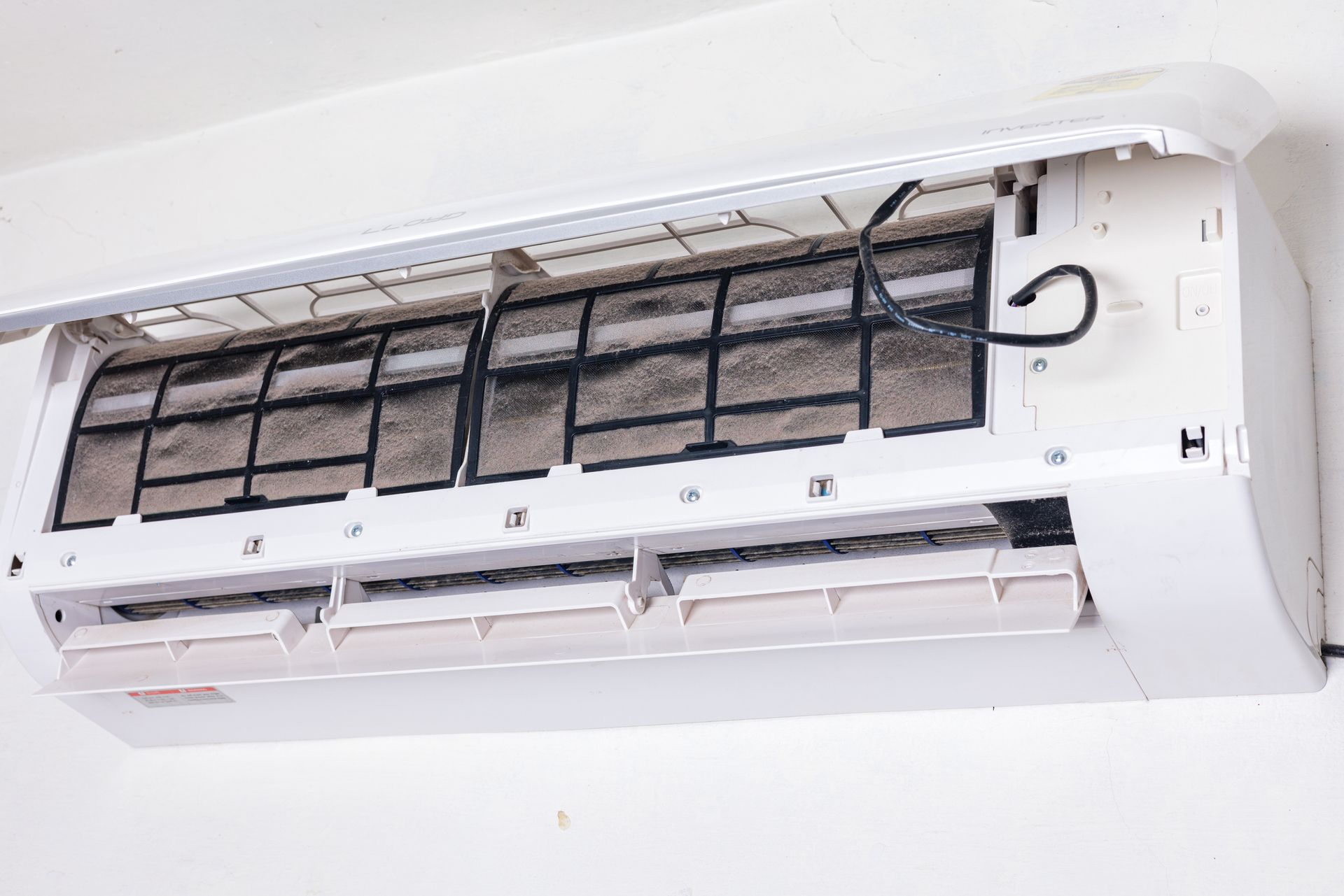 A close up of a dirty air conditioner on a wall.