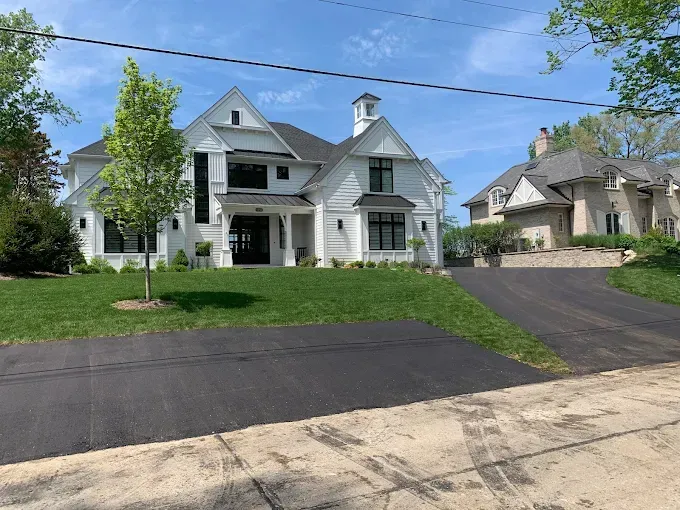 A large white house with a black driveway in front of it.