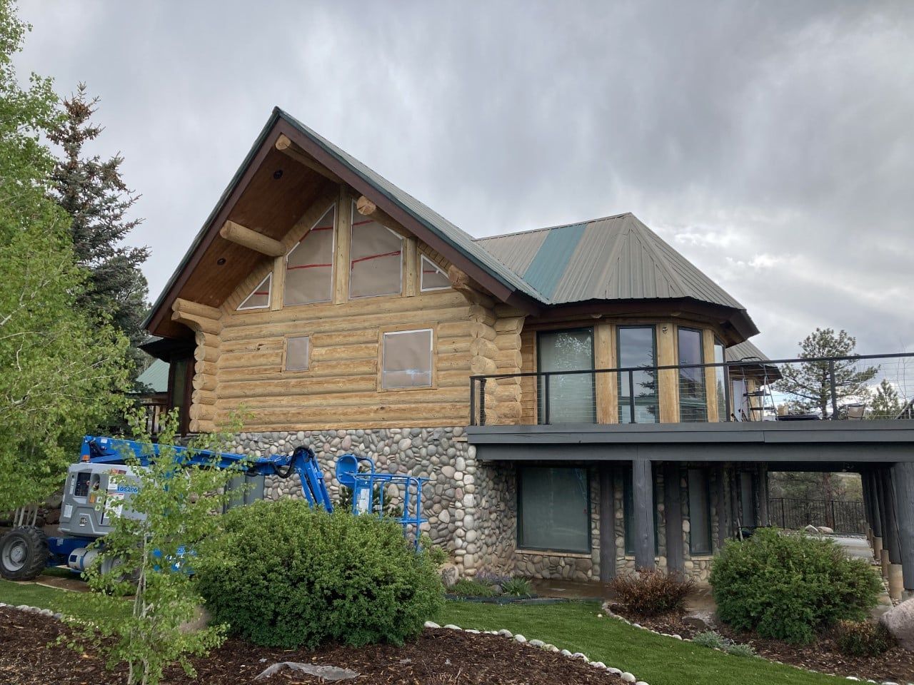 A large log cabin with a green roof is sitting on top of a lush green hillside.