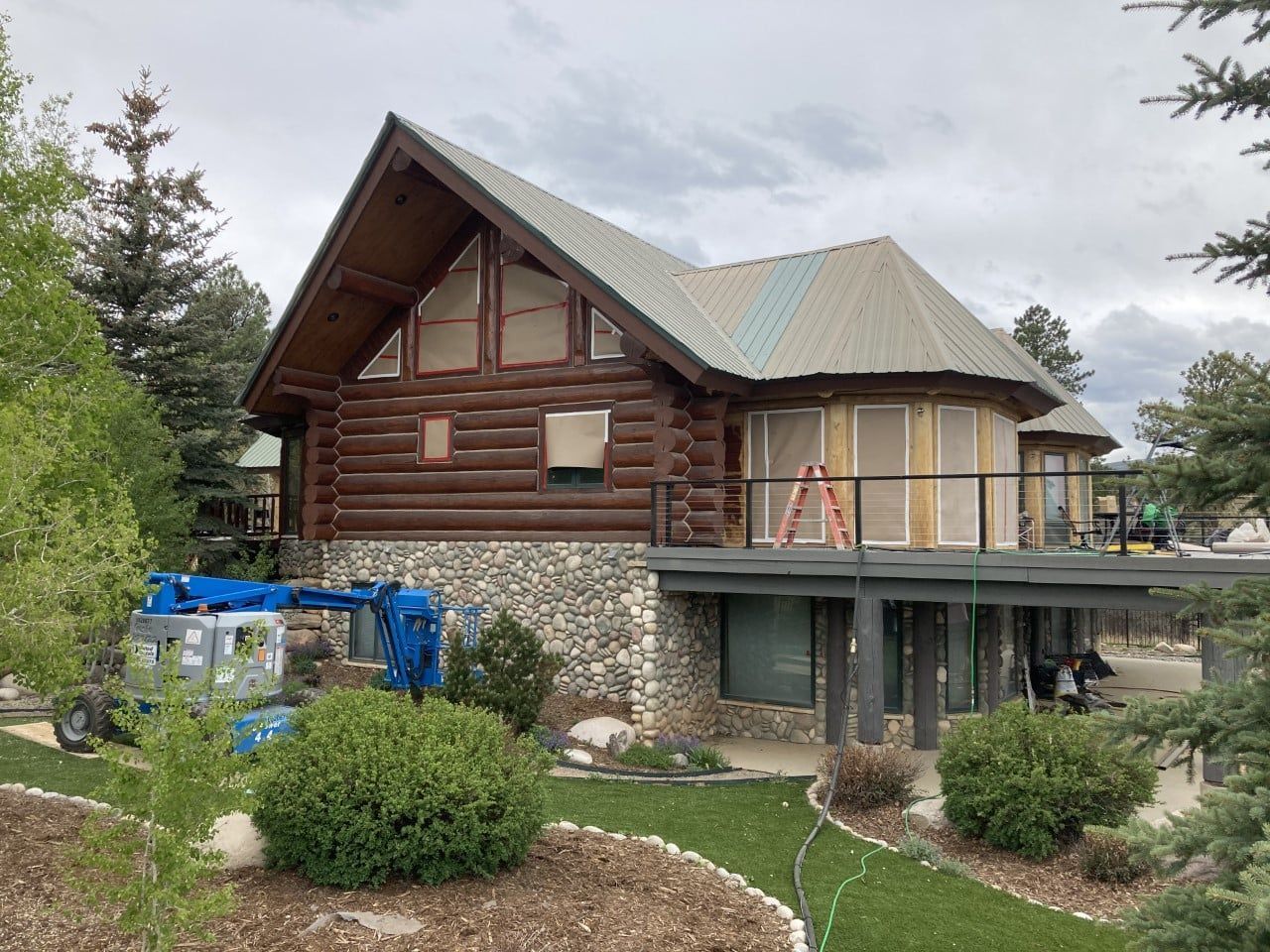 A large log cabin with a metal roof is being remodeled.