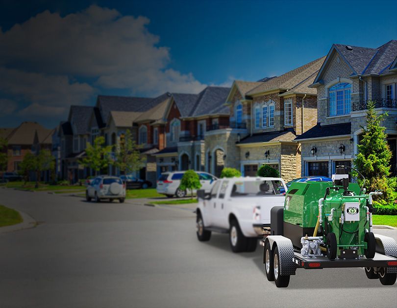 A white truck is pulling a green machine on a trailer.