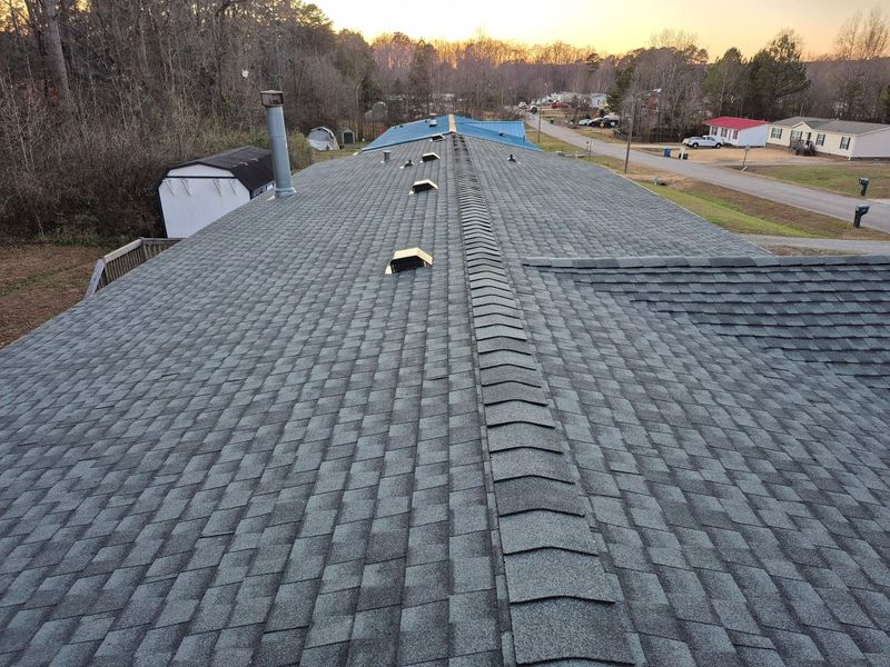 Aerial view of a gray asphalt shingle roof with ridge vents and chimneys