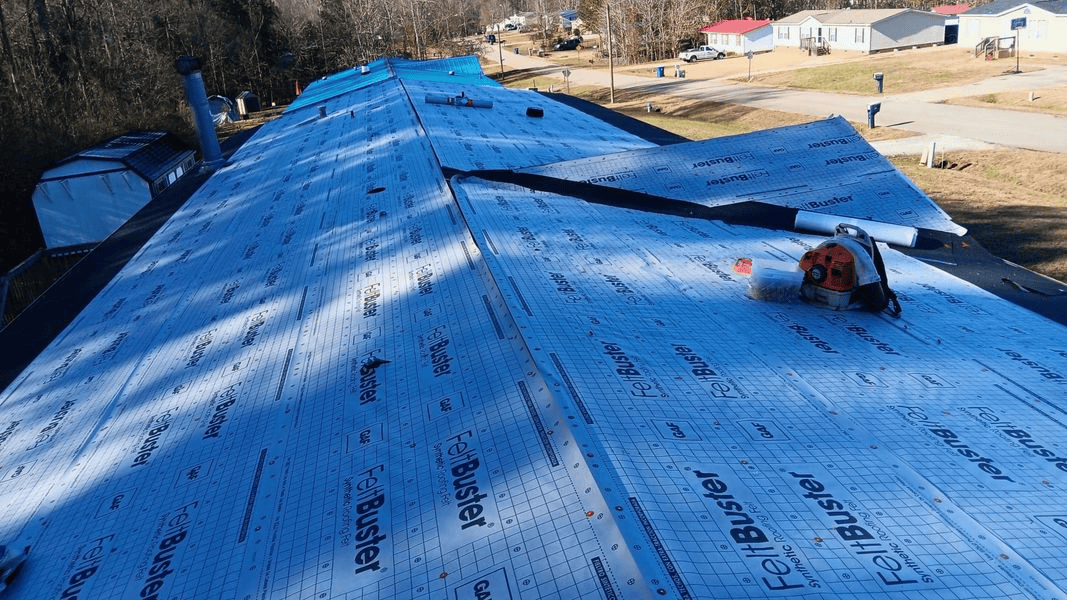 Rooftop covered in blue underlayment, a circular saw