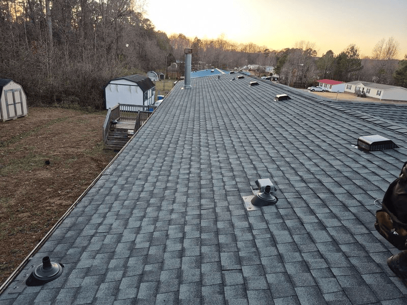 A long, gray asphalt shingle roof with vents