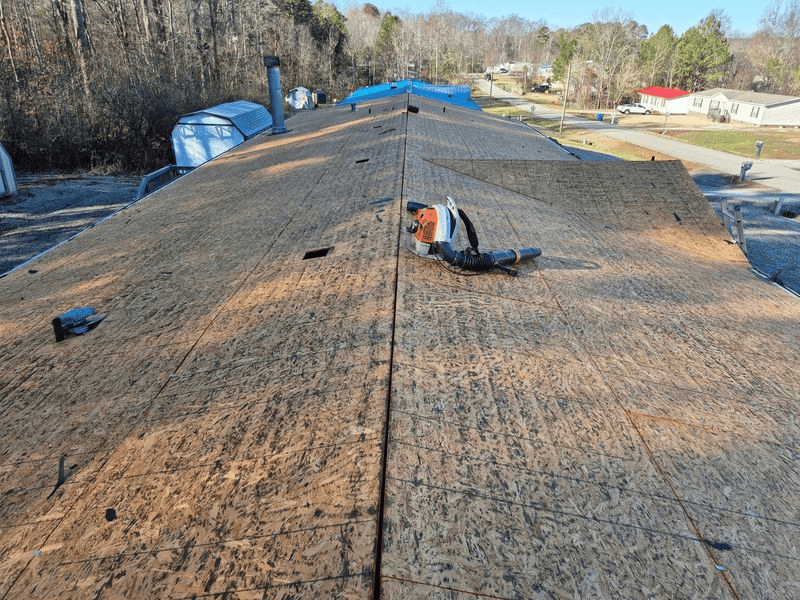 A person on a roof using a blower to clear debris