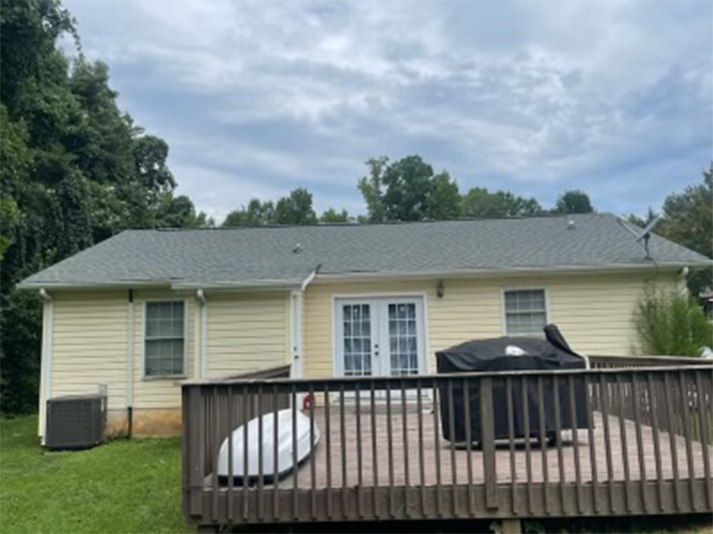 Back of a yellow house with a dark deck