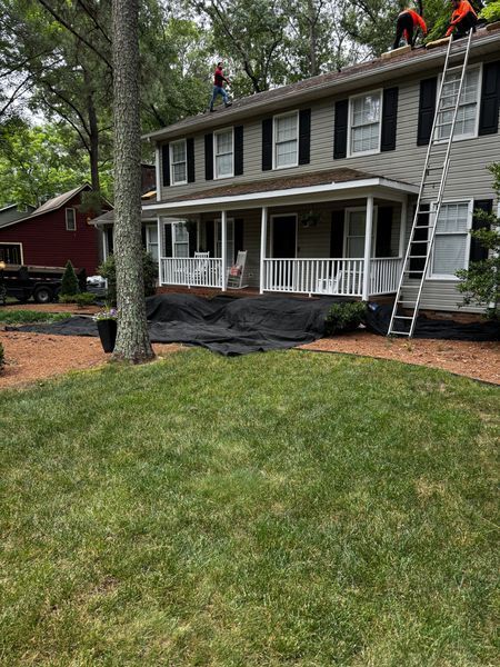 Roofers on a two-story house, using a ladder