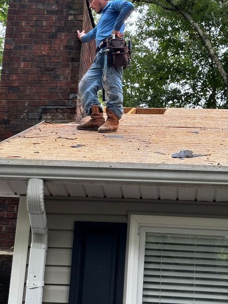 Roofer on a damaged roof near a brick chimney