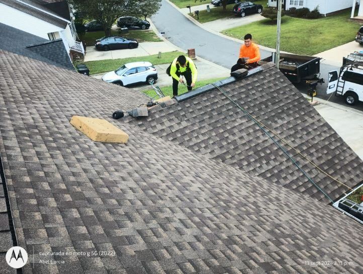 Two roofers repairing asphalt shingle roof
