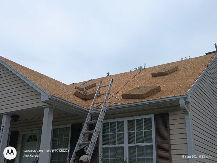 Roofers replacing shingles on a house under a cloudy sky