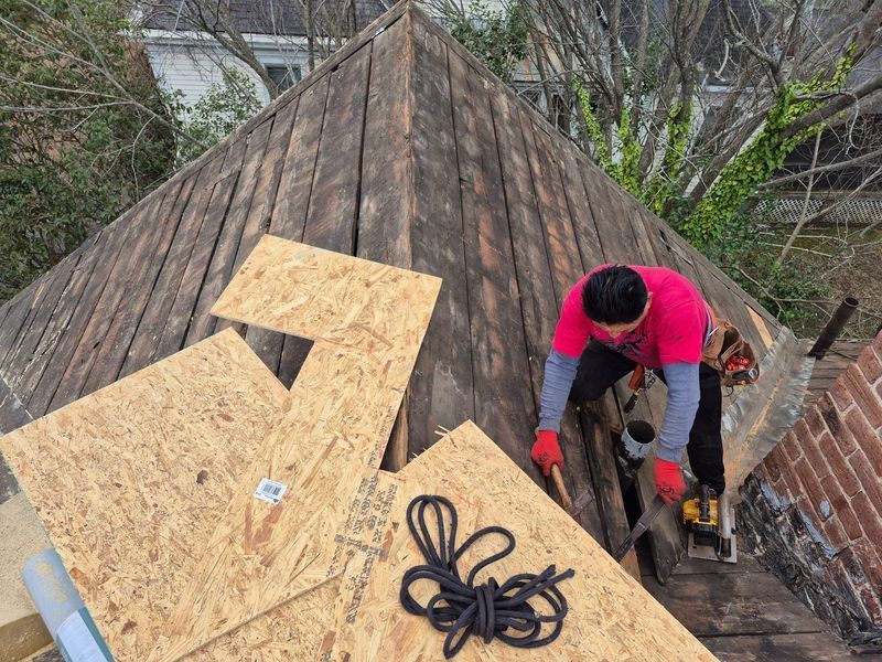 Roofer in pink shirt uses power tool to repair a wood roof
