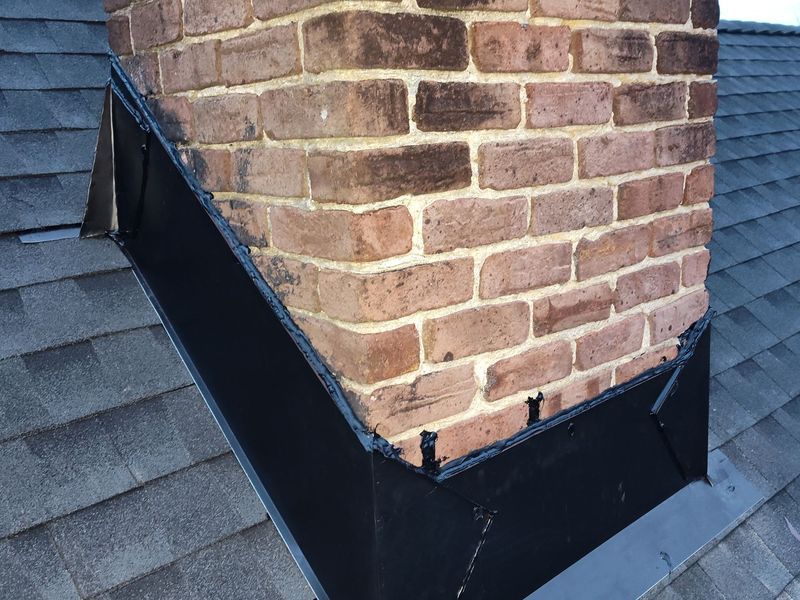 Chimney with black flashing against gray shingles