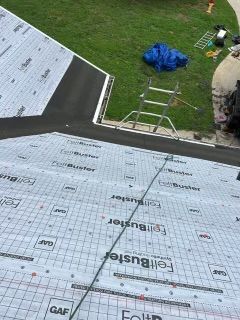 Roofing material installation on a house with green grass
