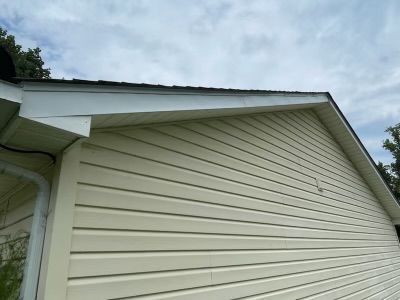 Beige vinyl siding on a house with a white eave