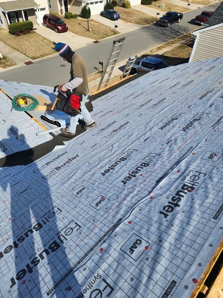 Roofer on a roof, applying roofing material on a sunny day