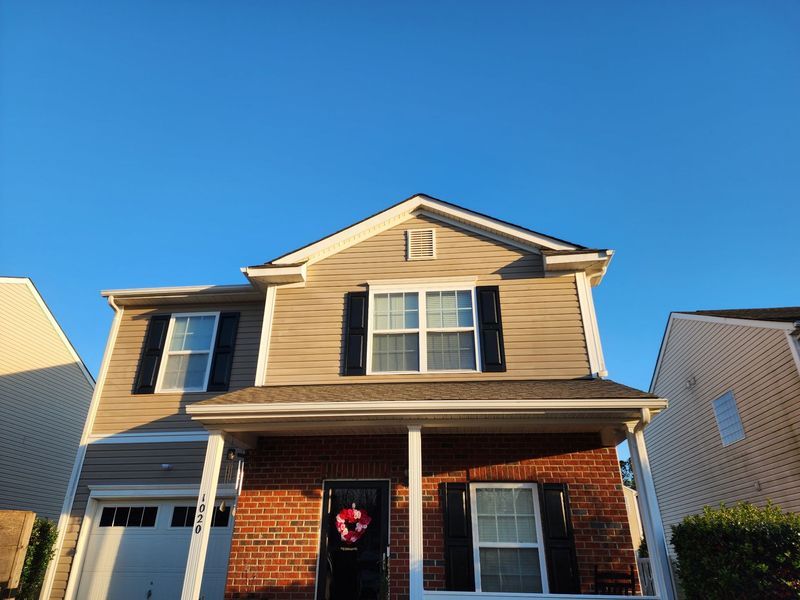 Two-story beige house with a red brick facade