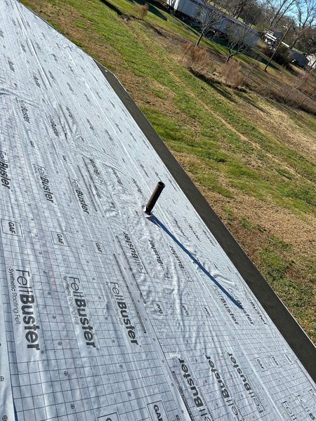 Rooftop covered in white underlayment with a pipe and metal edging
