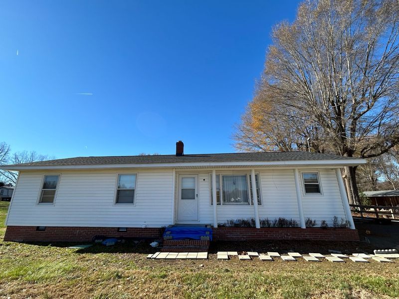 White ranch-style house with a brick base under a bright blue sky