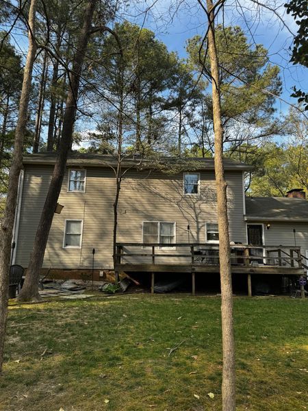Back of a two-story beige house with a wooden deck