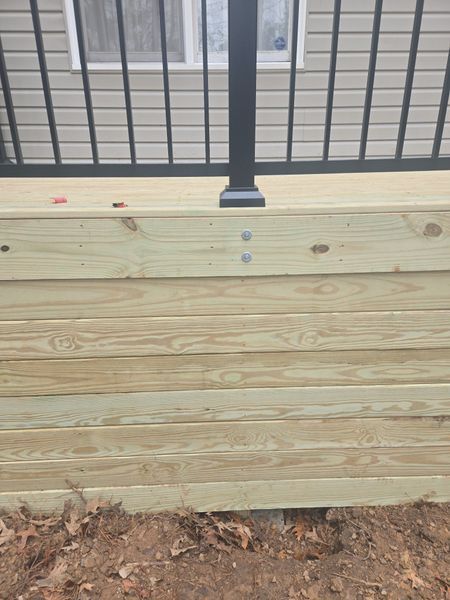 Close-up of a wooden deck railing post attached to a deck frame with bolts