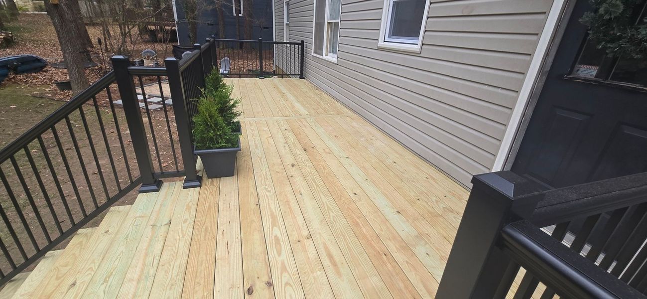 Newly constructed wooden deck with black railing and a small potted plant
