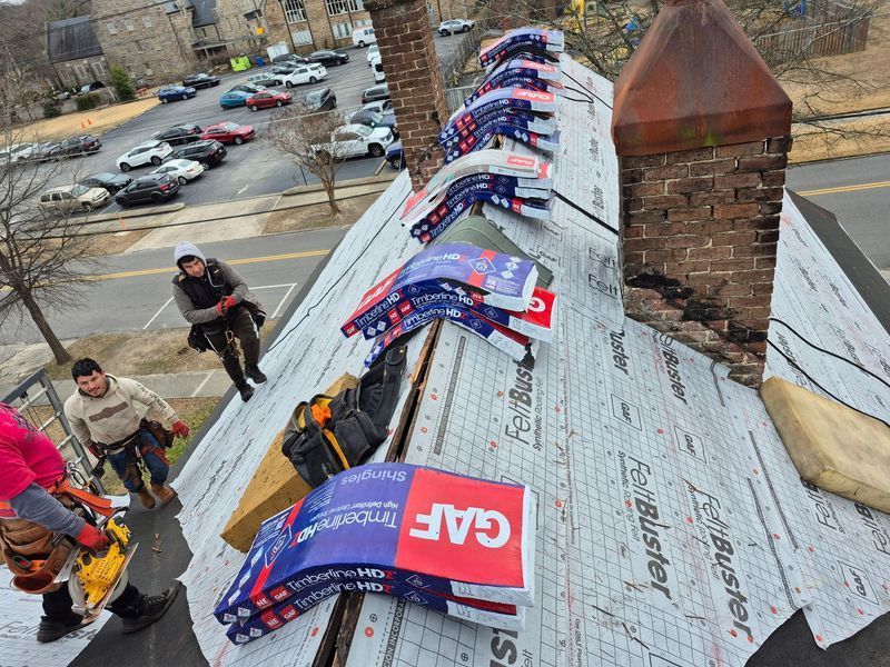 Roofers installing shingles on a sloped roof